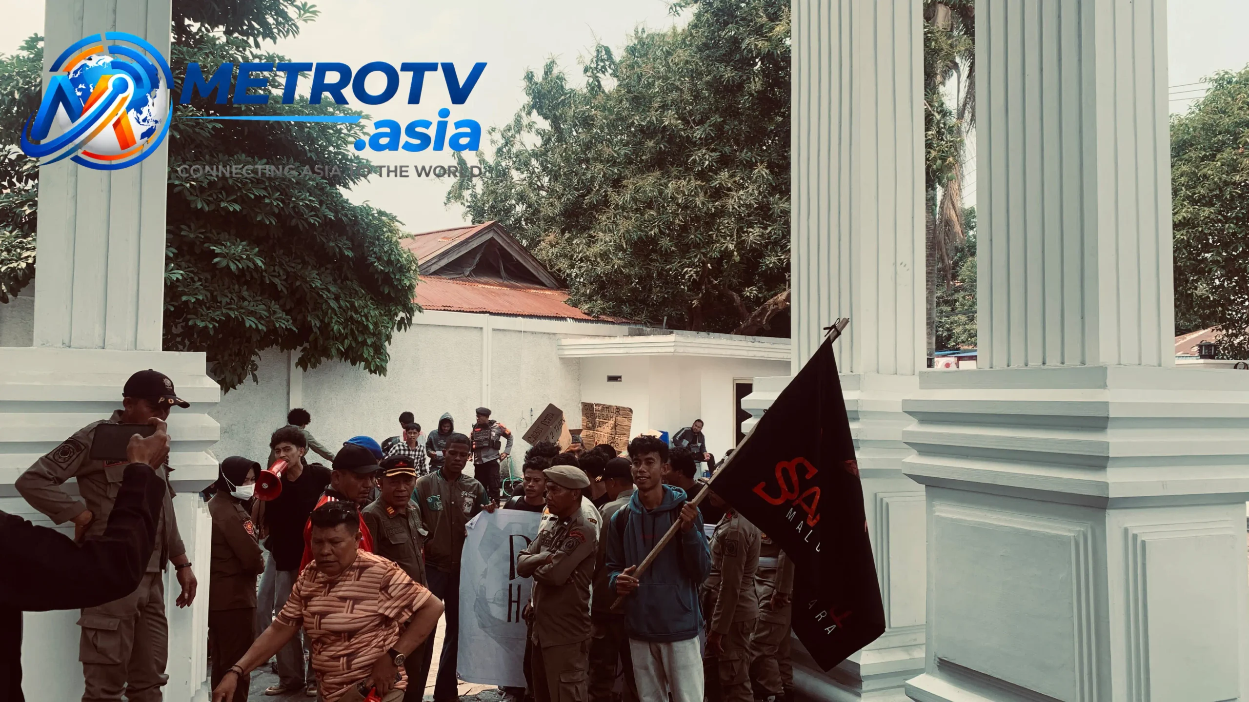 Massa aksi SAMURAI Maluku Utara berkumpul di halaman kediaman Gubernur, salah satu peserta mengibarkan bendera organisasi di hadapan petugas keamanan, Rabu 21 Oktober 2026